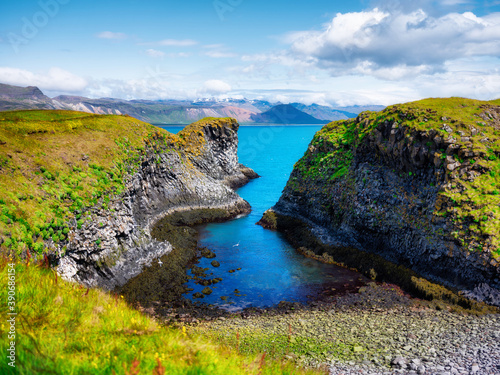 Seashore in Iceland. High rocks and grass at the day time near sea. Natural landscape at the summer. Icelandic travel image
