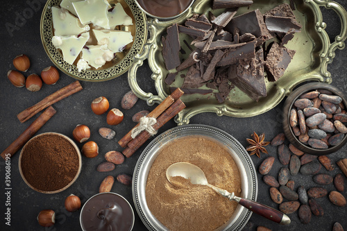 Dark chocolate in a composition with cocoa beans and nuts, on an old background.