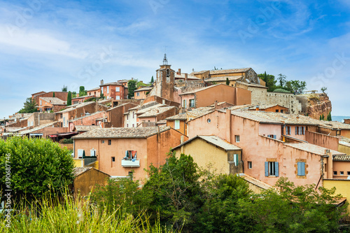 Old Provencal village on a cliff with houses from ocre clay behind bushes - Rousillon, Provence, France photo