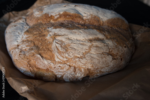 Bread baked in a wood oven. Close up of the piece of bread over the classic caste envelope on a black background.