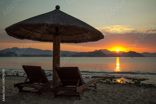 Sun loungers and umbrella by the sea. Sunrise by the sea. © Olga Min