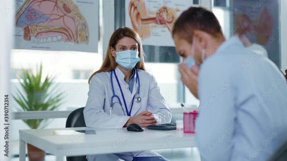 Portrait woman doctor in protective mask and lab coat sitting at desk in clinic. Speaking with man patient during consultation. In hospital. Pandemic coronavirus therapy. Slow motion Portrait woman doctor in protective mask and lab coat sitting at desk in clinic. Speaking with man patient during consultation. In hospital. Pandemic coronavirus therapy. Slow motion