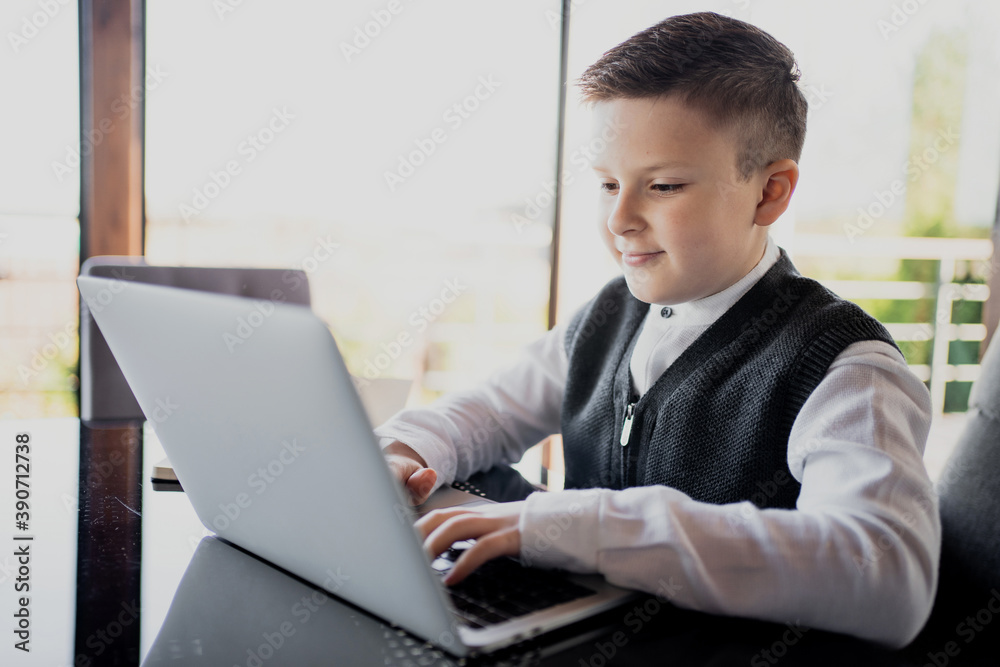 schoolboy boy with dark hair of European appearance does lessons online  with a teacher. dressed in a school white shirt and stylish hairstyle  holding a laptop. Stock Photo | Adobe Stock