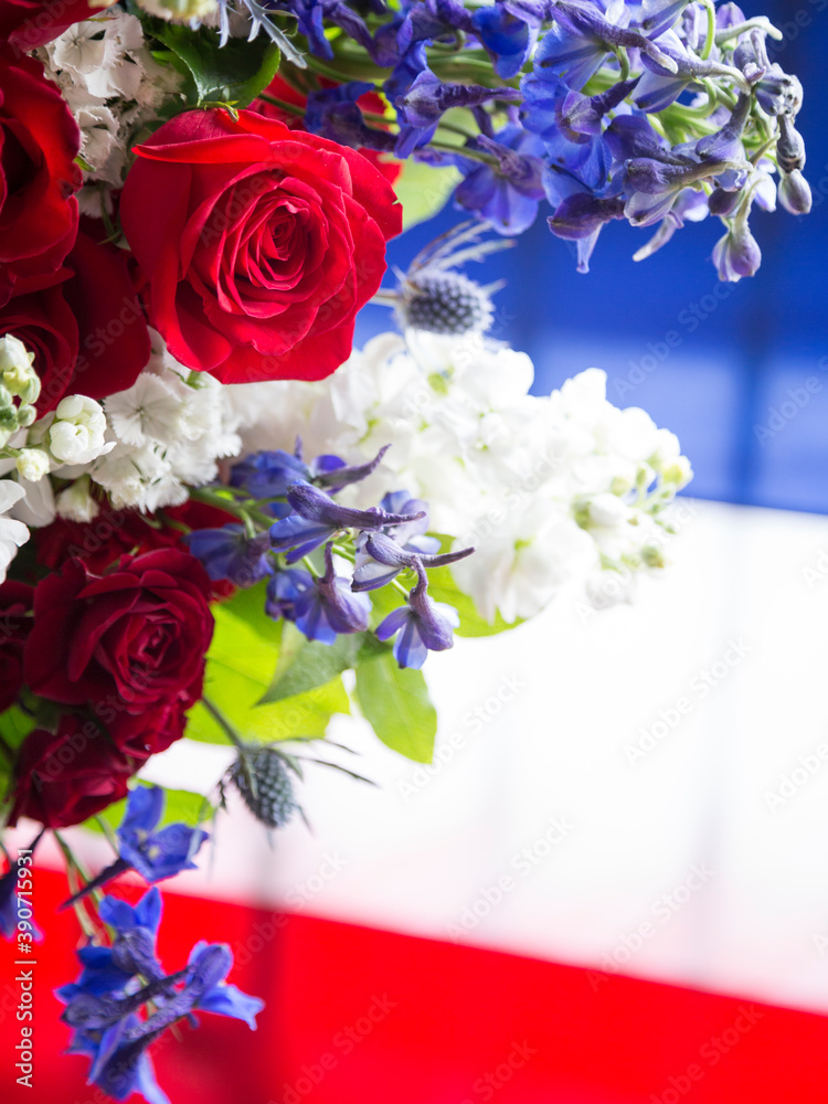 Red roses with white and blue flowers of a ceremonial wreath against a ...