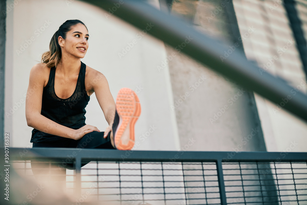 Fototapeta premium Smiling sportswoman doing warmup exercises before running.