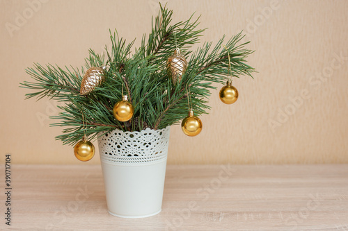 Small Christmas tree in a white bucket decorated with Christmas balls on the table