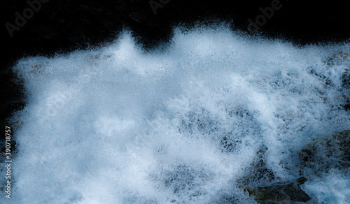 Water from a waterfall splashing down in large volumes with white foam and droplets. Isolated on black.