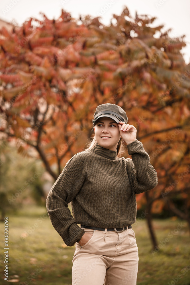 Young beautiful girl dressed in stylish clothes, green sweater and beige pants, in an autumn park with beautiful trees Young beautiful girl dressed in stylish clothes, green sweater and beige pants, in an autumn park with beautiful trees