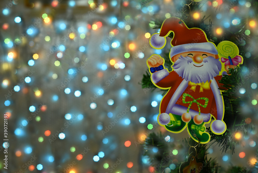 Beautiful multi-colored Christmas bokeh background. On the right side of the garland is a kind smiling Santa Claus on a Christmas tree branch.