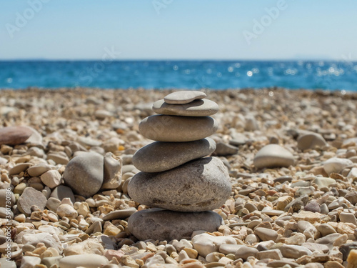 Pyramid of stones on Gjipe beach  Albania. Stacked rounded stones at sea - background. Relaxing in the beach. Blue sea and round stones