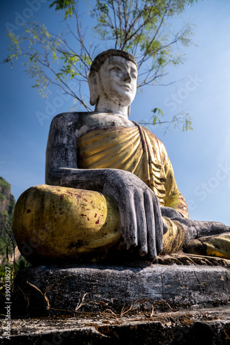 statue of buddha from below in front of a tree near Zwegabin Mount in Myanmar photo