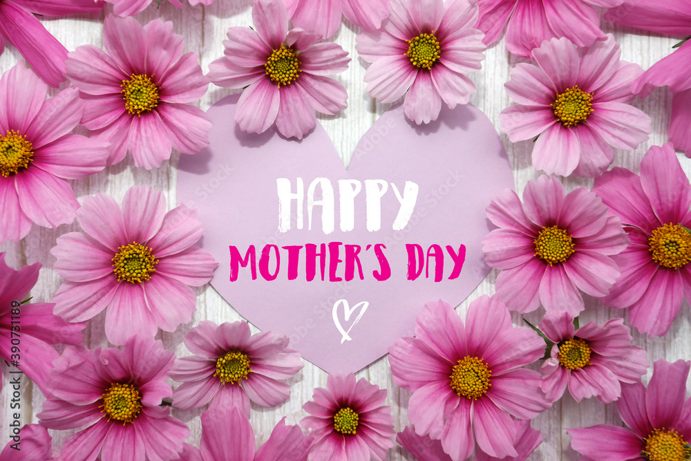 Happy Mothers Day. Background with frame of pink flowers, heart shaped card, text, white wood.