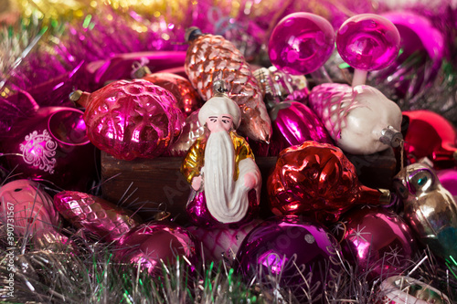 Old New Year's toys from the USSR in the form of cones, snowflakes, the bearded old man Hottabych, mushrooms and others. pink toys on a Christmas tree in a wooden box, silver tinsel. Background photo