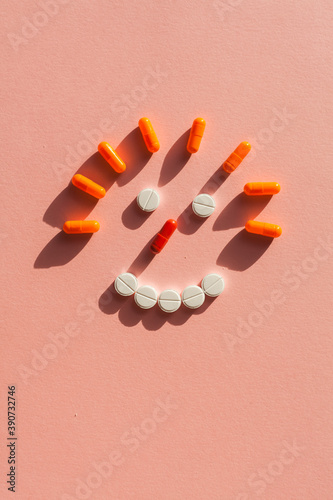 Smiling face from pills, tablets and capsules on pink background close-up top view flat lay. Concept of modern medical treatment, pharmacy, healthcare