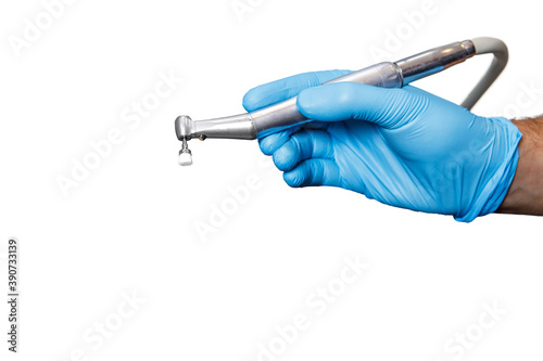 A dentist doctor holds a dental instrument on a white isolated background. The hand with the tool close up