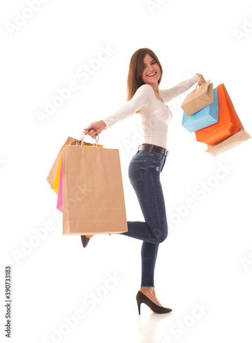 Girl smiles at the camera and holds the packages after shopping in her hands. Girl in high heels stands on white with shopping after sale. 