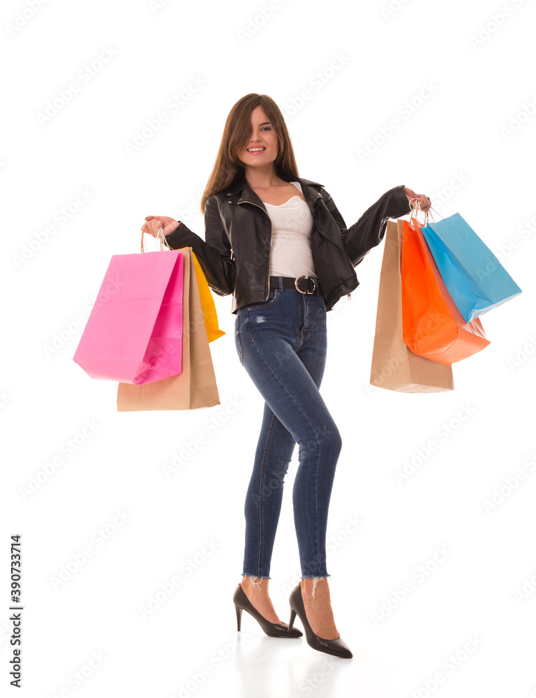 Girl smiles at the camera and holds packages in her hands. Brunette with new purchases in her hands after the sale. 
