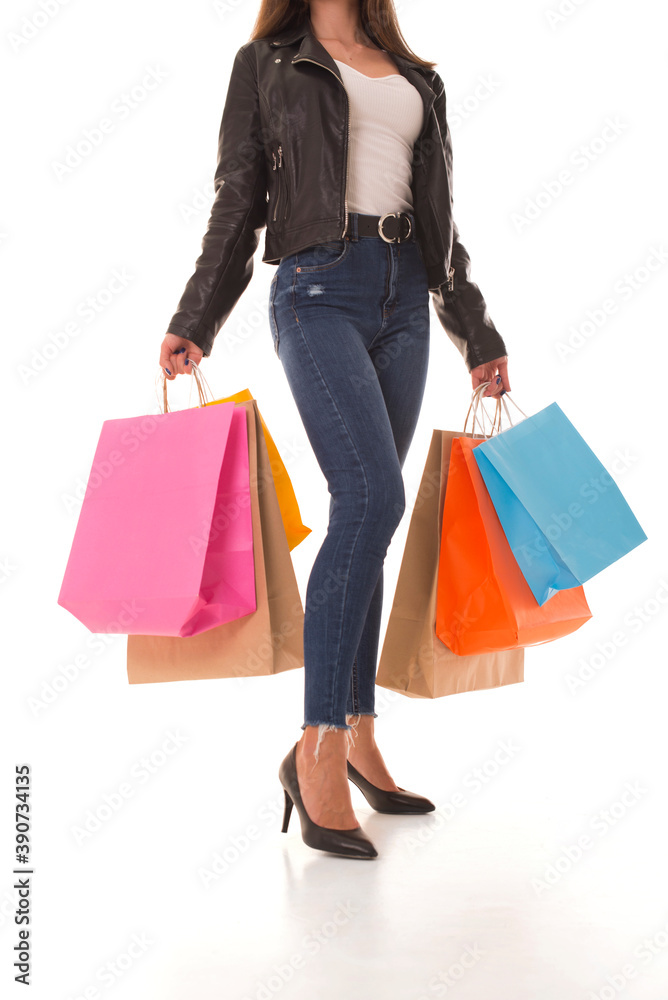 Girl in a leather jacket stands on a white background with purchases in her hands. Young girl with packages in hands. 