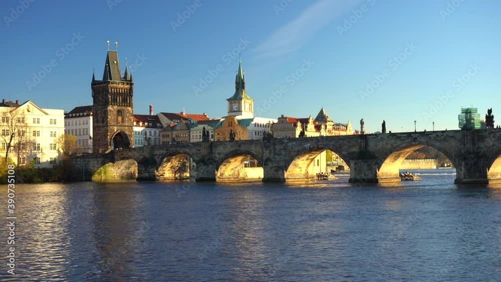 moving shot of the view of charles bridge and flowing river vltava in the center of prague at sunset the sky is blue in czech republic moving shot of the view of charles bridge and flowing river vltava in the center of prague at sunset the sky is blue in czech republic