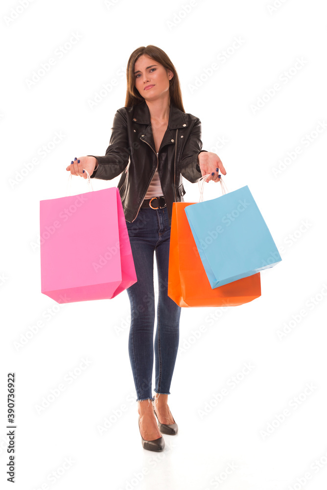 Girl looks at the camera in surprise while standing on a white background. Young girl with shopping after sale. 