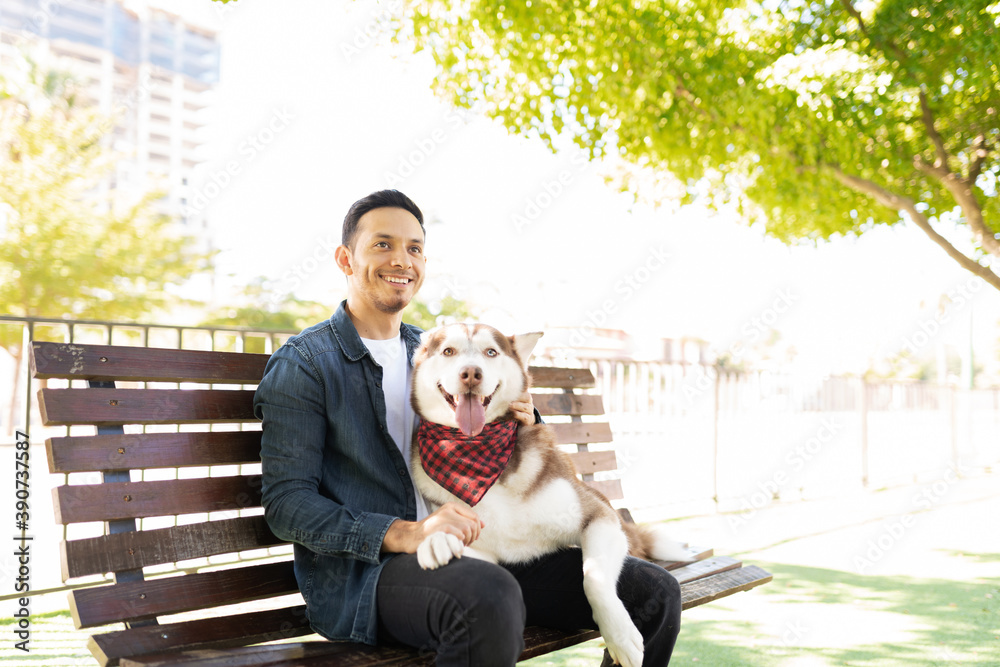 Latin man sitting with his dog buddy in a bench Latin man sitting with his dog buddy in a bench