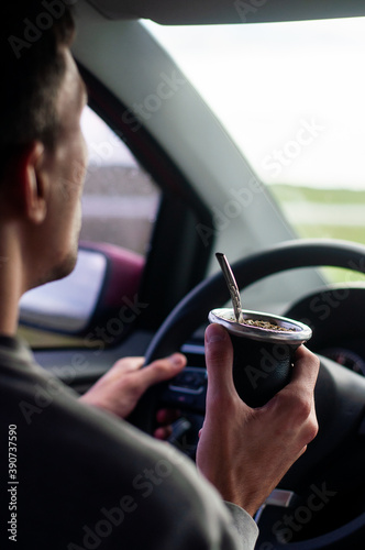 man driving drinking mate on the way to his travel destination on summer vacation
