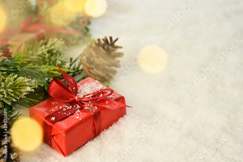 Christmas gifts boxes with red bows, pine cones, fir branches, snow and bokeh lights. Greeting card, mockup photo