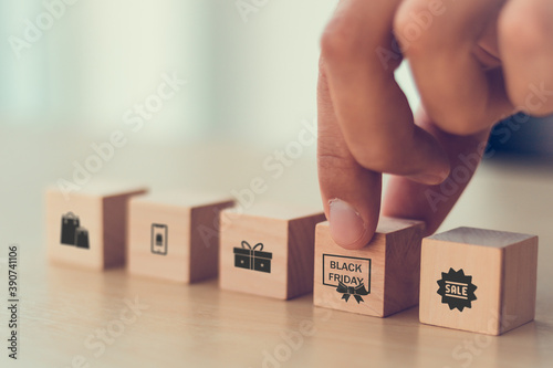 man hand arranging on wooden cube block with retail with black Friday day icon