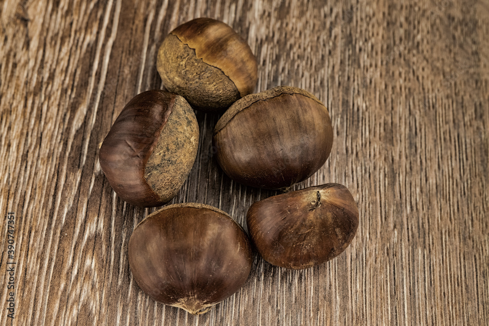 handful of brown edible chestnut on a wooden table handful of brown edible chestnut on a wooden table