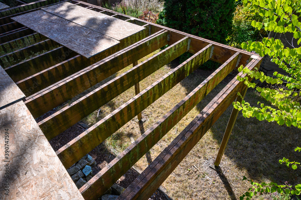 Summer construction, outdoor deck under construction, old support joists with plywood walkway on top
