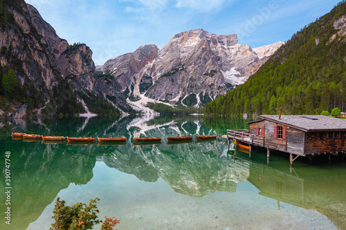 low angle view of Mount Seekofel and boatshouse mirroring in the clear calm water of iconic mountain lake Pragser Wildsee (Lago di Braies) in Dolomites, Unesco World Heritage, South Tyrol, Italy photo