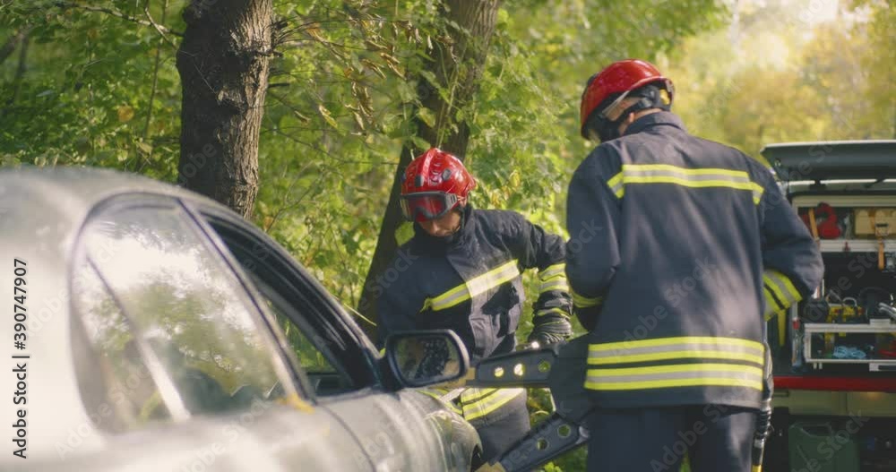Firemen disassembling damaged car after accident Firemen disassembling damaged car after accident