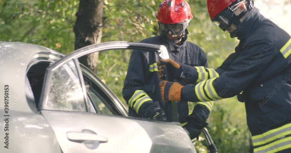 Firefighters removing car door in countryside Firefighters removing car door in countryside