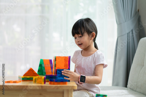 A 5 years old asian little girl is pay attention to build the house toys fro the magnetic blocks, concept of learn through play, home based learning and education toy for kid.