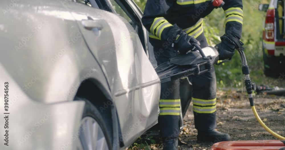 Anonymous firemen removing broken door from crashed car Anonymous firemen removing broken door from crashed car