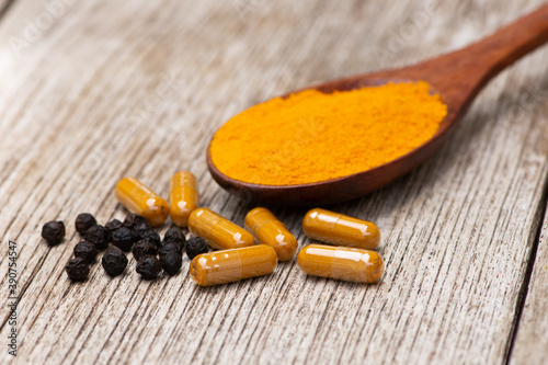 Curcuma capsules and black pepper ( peppercorns or piperine ) with Turmeric ground or tumeric powder photo