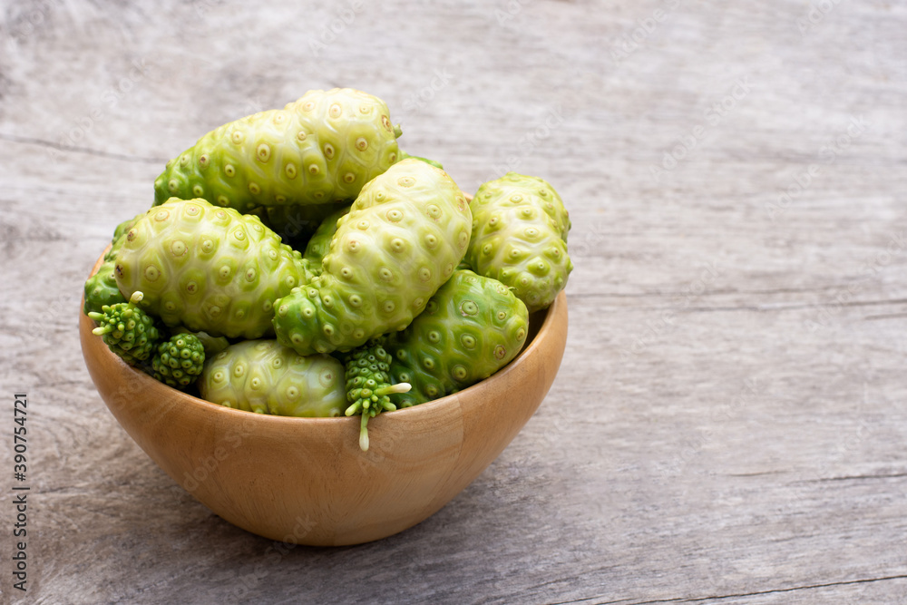 Fresh Noni fruit in wooden bowl isolated on wooden table background. Fresh Noni fruit in wooden bowl isolated on wooden table background.