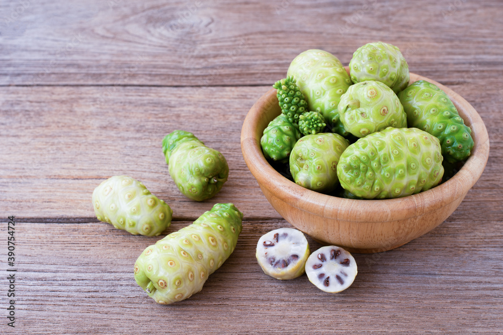 Fresh Noni fruit in wooden bowl isolated on wooden table background. Fresh Noni fruit in wooden bowl isolated on wooden table background.