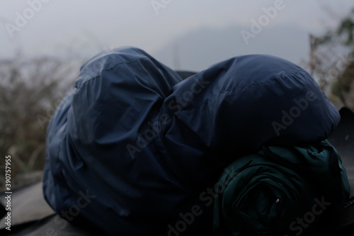 rear view of person in blue hood jacket sleeping on outdoor with foggy morning