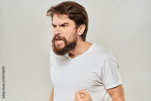 bearded man gesturing with his hands in a white t-shirt aggression light background photo