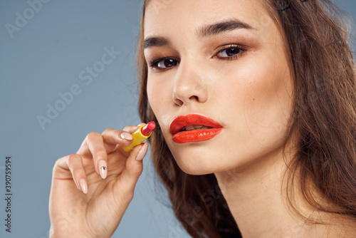 Woman with lipstick on a gray background brunette makeup with eye shadow on the eyelids