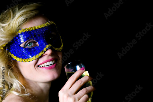 The woman is drinking champagne wine. Blue carnival mask.