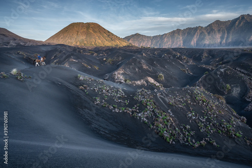 Bromo National Park, East Java, Indonesia - October 16, 2020 : Tengger man riding his horse in the distance, on the black sand savanna of Mt Bromo