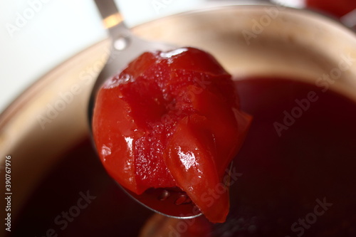 Removing boiled tomato from saucepot to blending. Making soup. photo