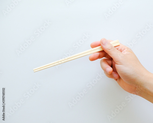 hand holding chopsticks isolated on white background, copy space template for banner, kitchen equipment, a product from nature 