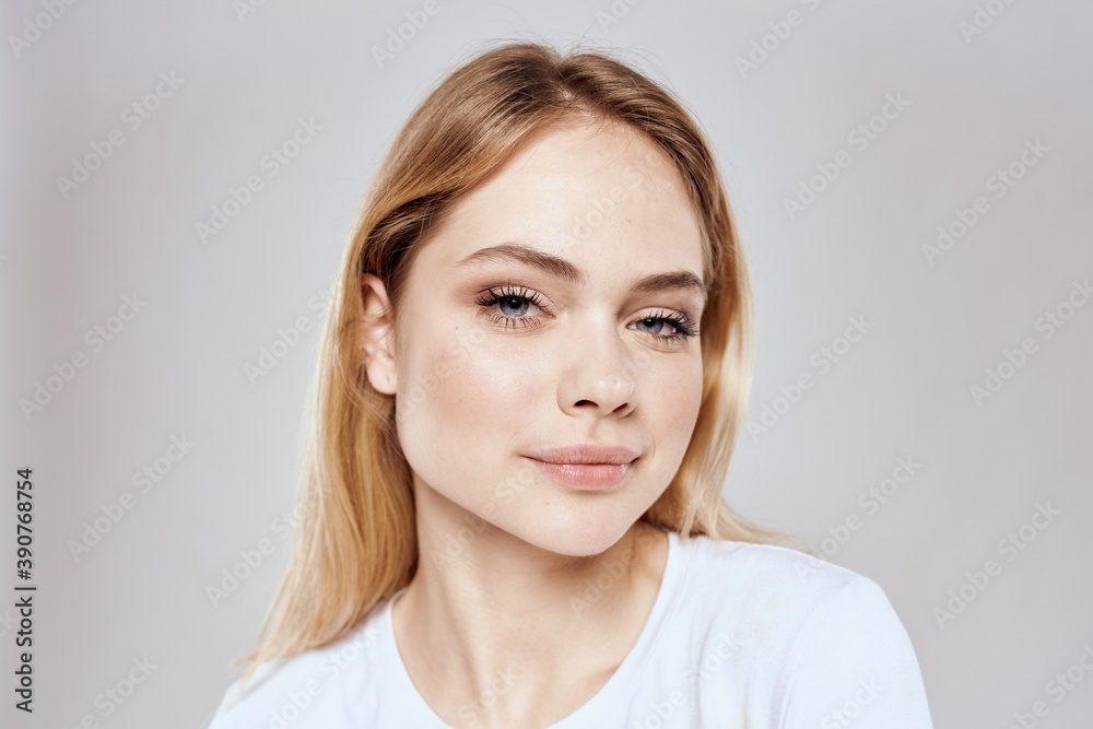 Cheerful blonde woman in white t-shirt cropped view light background Cheerful blonde woman in white t-shirt cropped view light background