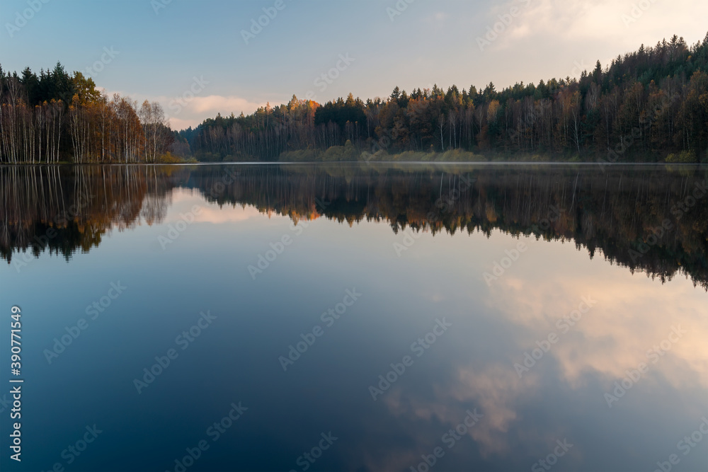Czech autumn foliage trees landscape reflected in Rimov dam with misty fog