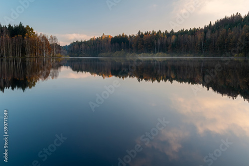 Czech autumn foliage trees landscape reflected in Rimov dam with misty fog