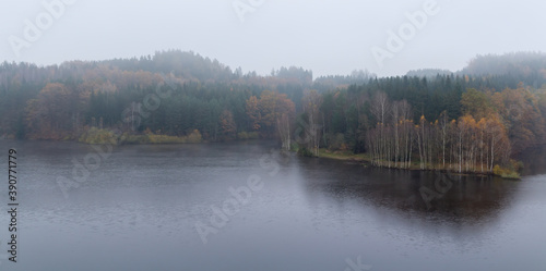 Czech autumn foliage trees landscape on Rimov dam in misty fog