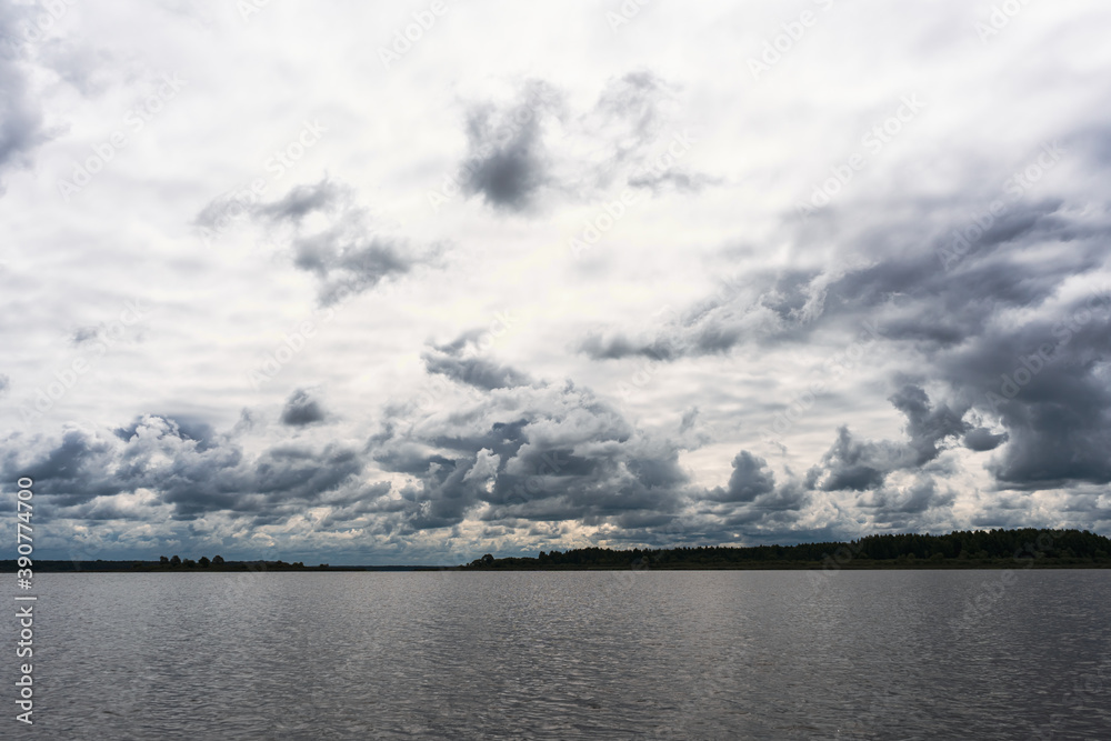 Gray colors of the sky with dark clouds over an autumn lake in Russia